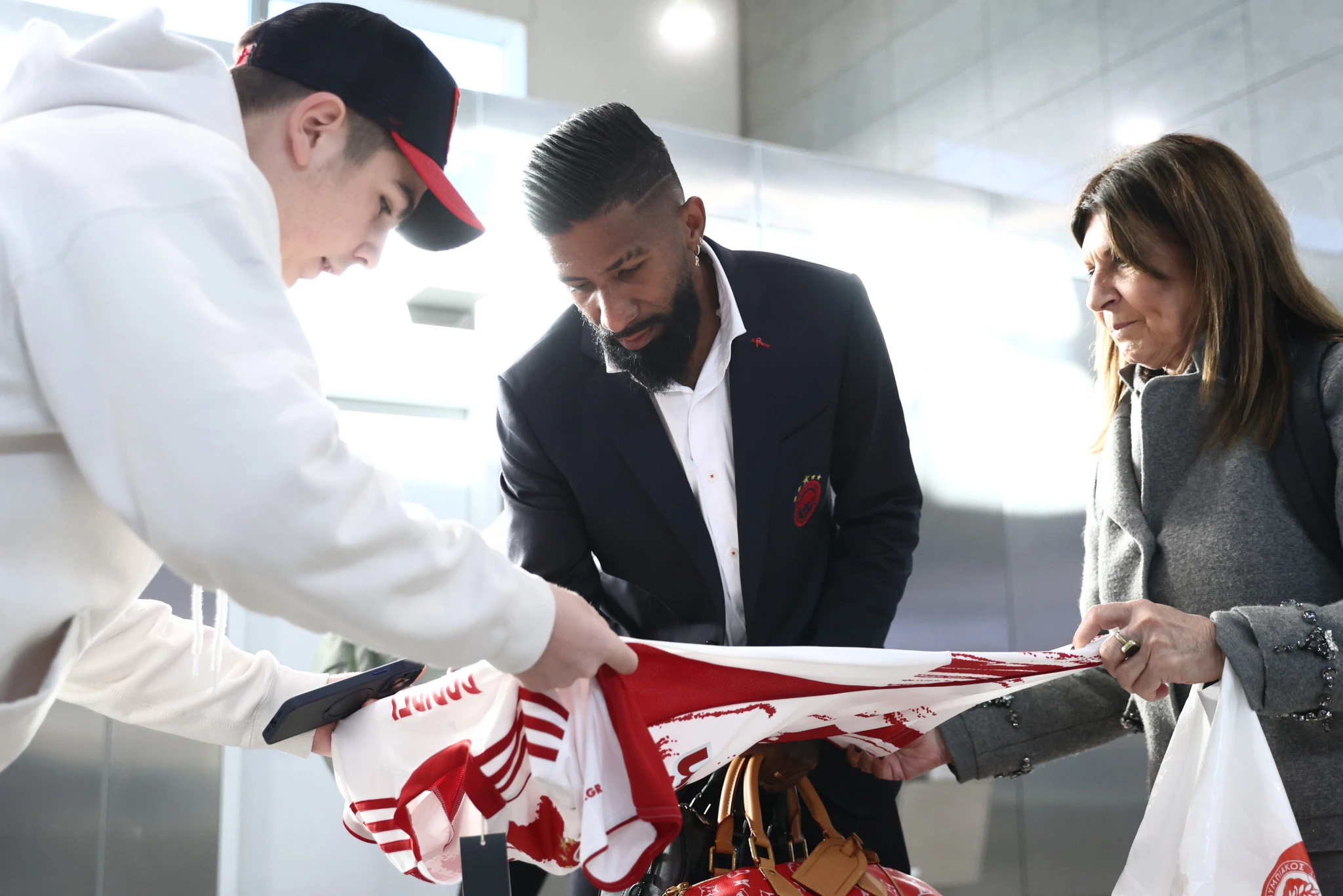 Ο Ροντινέι υπογράφει την φανέλα οπαδού του Ολυμπιακού / Πηγή: Intime