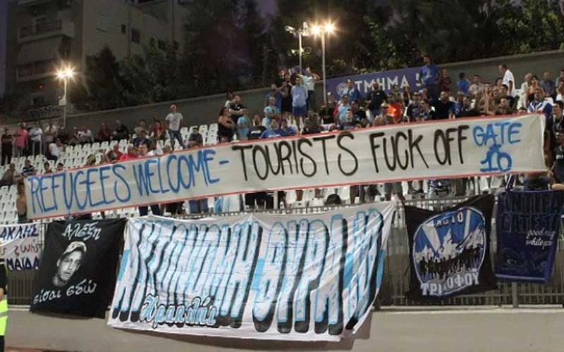 Το πανό «Refugees welcome – Tourists fuck off