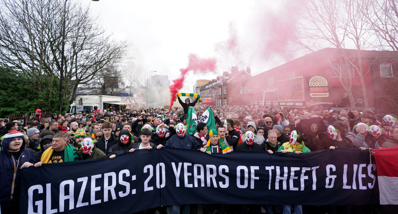 Ο... λαός της Μάντσεστερ Γιουνάιτεντ με μάσκες κλόουν διαμαρτύρονται για τις πρακτικές της διοίκησης / Πηγή: Martin Rickett / PA Images via Getty Images
