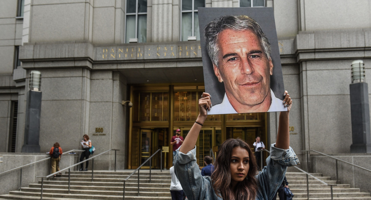Μέλος της ομάδας διαμαρτυρίας «Hot Mess» κρατάει πινακίδες του Τζέφρι Έπσταϊν μπροστά από το ομοσπονδιακό δικαστήριο στις 8 Ιουλίου 2019 στη Νέα Υόρκη / Πηγή: Stephanie Keith / Getty Images