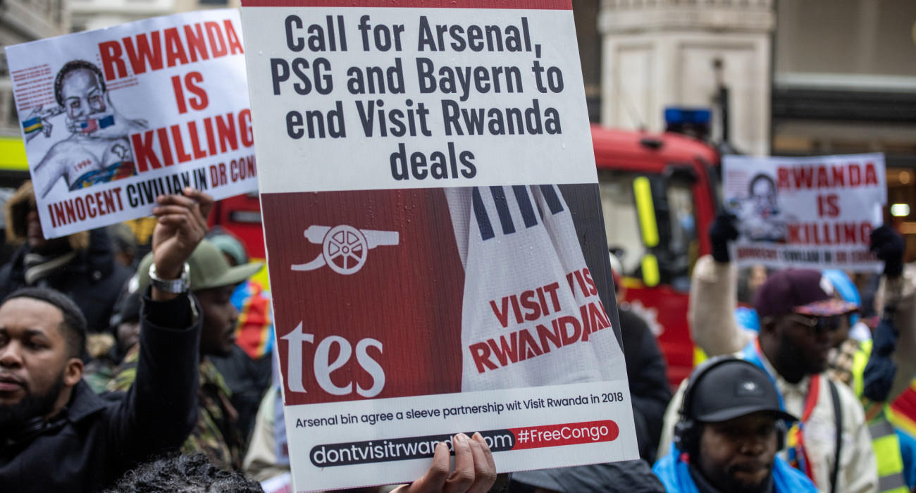 Ένας διαδηλωτής κρατάει πλακάτ και απαιτεί από Άρσεναλ, Μπάγερν Μονάχου και Παρί να σταματήσουν τις συμφωνίες «Visit Rwanda» / Πηγή: Krisztian Elek / SOPA Images / LightRocket via Getty Images